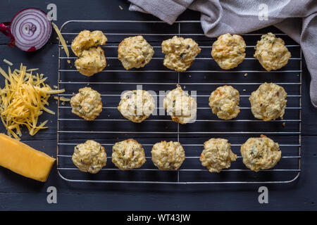 Mini savoury cheese and onion muffins out of oven on cake cooling grid - top view of cheesy appetizer biscuit Stock Photo