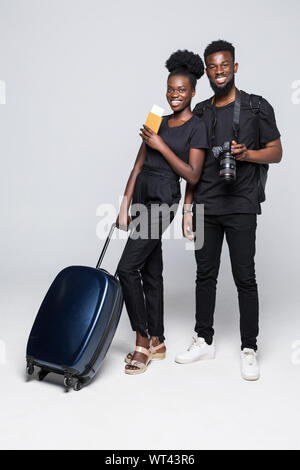 Full length portrait of young african couple walking with suitcases for travel isolated over white background Stock Photo