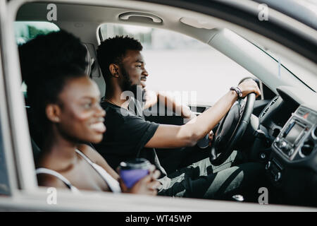 leisure, road trip, travel, family and people concept - happy man and woman driving in car with coffee Stock Photo