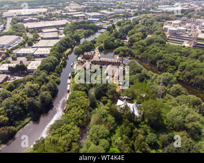 Aerial footage of The Made in Leeds Festival located at the Thwaite Mills along the side of the Leeds Canal showing the water and waterfall on a sunny Stock Photo