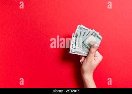 A pack of one hundred dollar bills in female hand on colorful background. Salary concept with copy space. Stock Photo