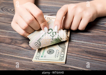Perspective view of a businesswoman's hands counting fifty and twenty dollar banknotes on wooden background. Success and wealth concept. Stock Photo