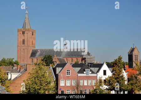 Historic houses located inside the fortified town of Naarden, Netherlands, with the clock tower of the Grote Kerk church in the background Stock Photo