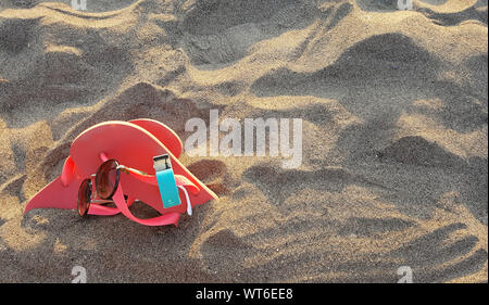 Beach slippers and sunglasses in the sand Stock Photo