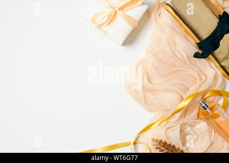Female workspace with scarf, golden accessories, clutch bag, ribbon, gift box, perfume on white background. Flat lay beauty blogger home office desk w Stock Photo