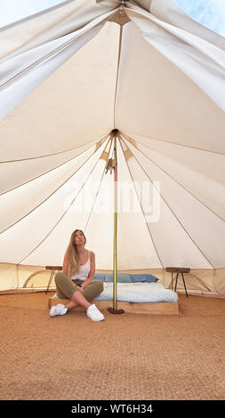 Young woman contemplating the interior of an enormous camping tent Stock Photo