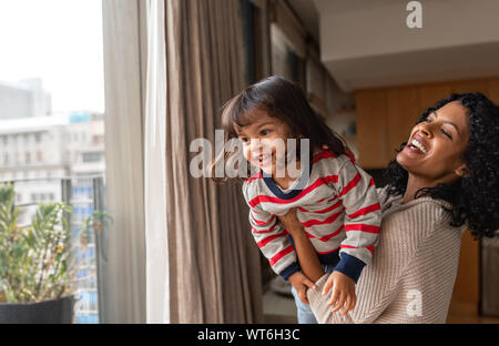 Laughing mother and small daughter playing together at home Stock Photo