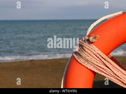 Life buoy on a pole on a sandy beach with blue sea water in Tuscany, Italy. Stock Photo