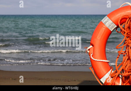 Life buoy on a pole on a sandy beach with blue sea water in Tuscany, Italy. Stock Photo