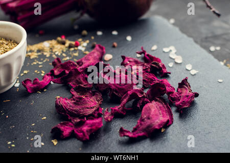 Healthy homemade vegetable chips from beetroot with salt, pepper and origano on black background. Organic diet food. The vegan diet. Dried vegetables. Stock Photo