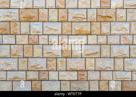 Bright stone wall of exactly square rough natural stones Stock Photo