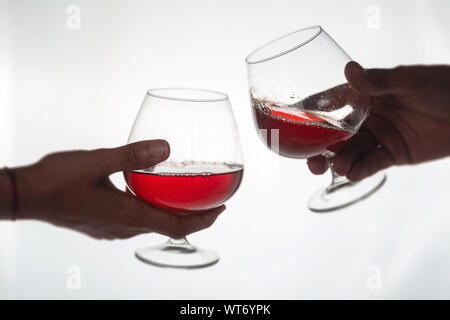 Cheers. Close-up of two people toasting with red wine at the bar counter Stock Photo