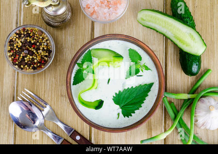 Traditional greek dip sauce or dressing tzatziki prepared with grated cucumber, yogurt, olive oil and fresh dill on wooden table in ceramic bowl. Stud Stock Photo