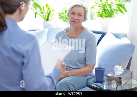 Counseling concept: psychotherapist taking notes during a therapy session with her upset female patient. Stock Photo