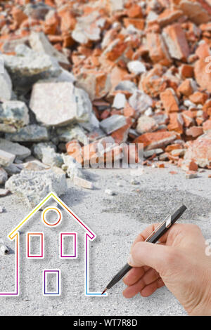 Hand drawing a colored house against a concrete and brick rubble debris - earthquake reconstruction concept image Stock Photo
