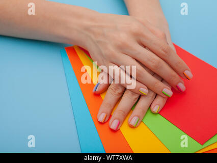 Modern stylish manicure rainbow or summer mood, on a blue table with color envelopes. Close-up Stock Photo