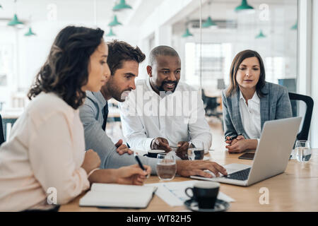 Diverse businesspeople smiling while working together on a laptop Stock Photo