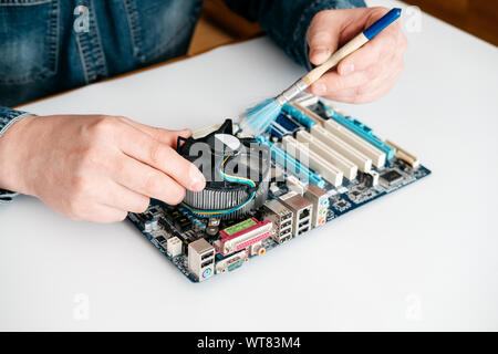 Technician using brush for computer cleaning, clean the motherboard from dust Stock Photo