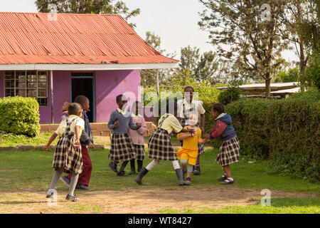 Imani Junior Academy, Nanyuki, Laikipia county, Kenya – June 13th, 2019: Candid photograph of young school children playing with a white girl who was Stock Photo