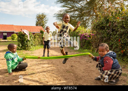 Imani Junior Academy, Nanyuki, Laikipia county, Kenya – June 13th, 2019: Candid photograph of young school children skipping with an improvised rope o Stock Photo