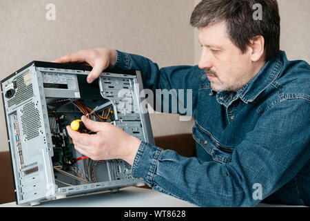 Computer technician engineer with screwdriver in his hand is repairing the personal computer. Concept of computer hardware, repairing, upgrade and tec Stock Photo