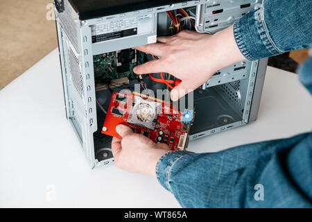 Repairman is take off graphic processing unit from personal computer. Engineer is diagnostic and fixing broken pc in workshop. Electronic repair shop, Stock Photo