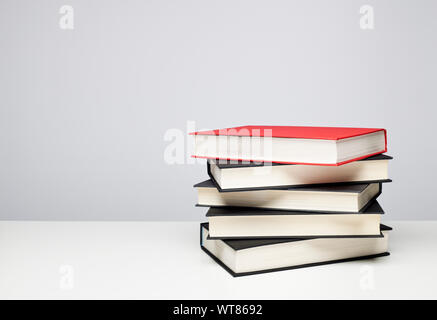Stack of books. Four black and one red hardback books on a table Stock Photo