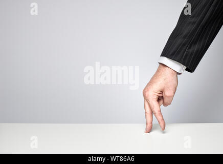 Businessman with fingers walking along a table Stock Photo