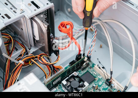Hand of computer engineer with screwdriver is mount computer motherboard. Stock Photo