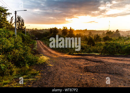 Creative colour landscape photograph of red gravel road with only foreground in-focus during sunrise, taken in Nanyuki, Kenya. Stock Photo