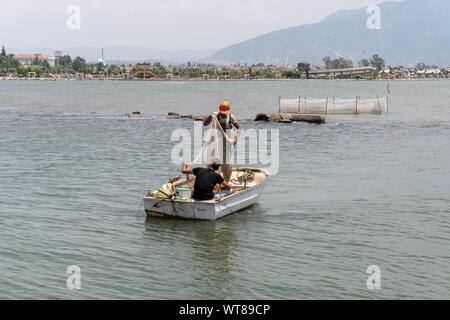 Two men fishing from small boat with net and paddle Yen River