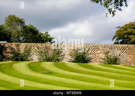 Lawn stripes leading up to a stone wall with fruit trees being trained on espaliers 2 Stock Photo