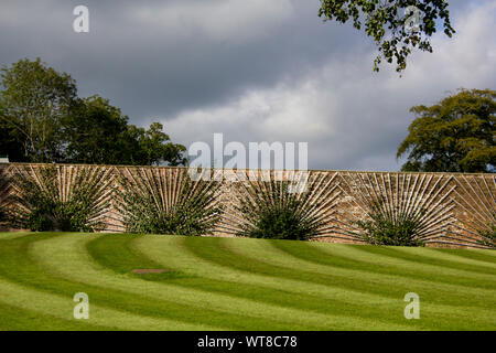 Lawn stripes leading up to a stone wall with fruit trees being trained on espaliers 3 Stock Photo