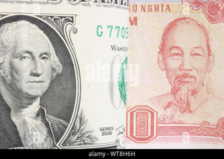 US President Washington on a bent 1 dollar bill. Close-up. Against the background of a portrait of Ho Chi Minh City on a Vietnamese banknote of 500 do Stock Photo