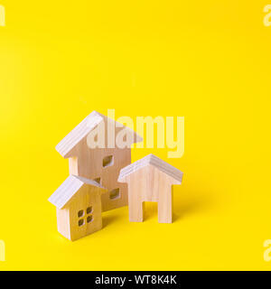 Three houses on a yellow background. Buying and selling of real estate, construction. Apartments and residential buildings in a city or settlement. In Stock Photo