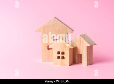Three houses on a pink background. Buying and selling of real estate, construction. Apartments and residential buildings in a city or settlement. Inve Stock Photo