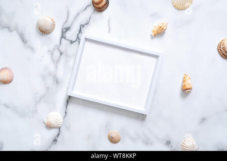 Sea shells and blank picture frame with copy space for your text on marble background. Summer vacation concept. Flat lay, top view, overhead. Stock Photo