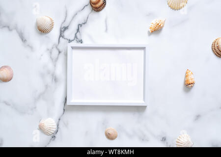 Sea shells and blank picture frame with copy space for your text on marble background. Summer vacation concept. Flat lay, top view, overhead. Stock Photo