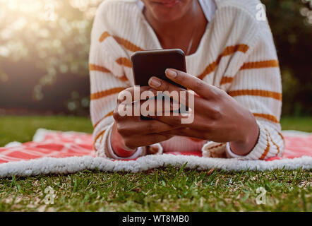 Woman hand holding and using smart phone while relaxing in the park Stock Photo