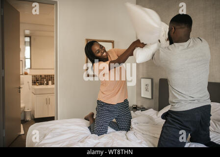 African American couple having a fun pillow fight in bed Stock Photo