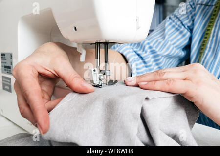 Close-up partial view of seamstress working with sewing machine and textile fabric at atelier workshop Stock Photo