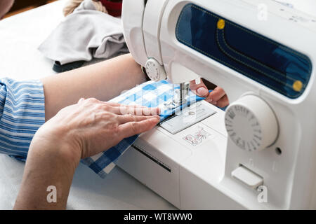Hands of a woman using a sewing machine in tailor workshop. Stock Photo