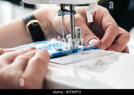 Hands of a woman using a sewing machine in tailor workshop. Stock Photo