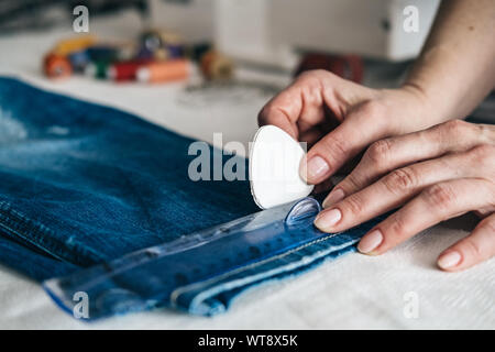 Seamstress marking hem on a pair of 