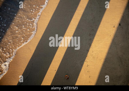 Strong lines of light and shadow on the sandy beach of the London river Thames. Stock Photo
