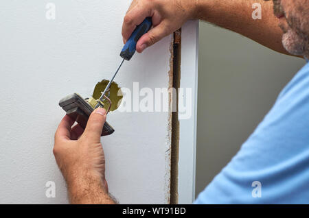 Hands holding an old switch and screwdriver while detaching it Stock Photo