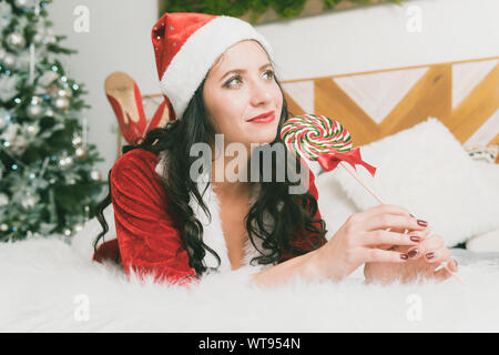 Funny Christmas Girl Holding a Candy Lollipops. Beautiful expressive woman in sweet Christmas fantasy portrait with lollipops Stock Photo
