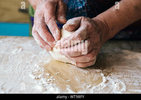 Wrinkled hands of older woman kneading dough Stock Photo