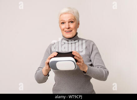Senior woman amazed of virtual reality after using VR headset Stock Photo