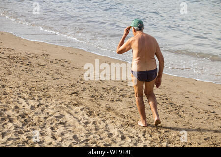 Rear view of old man walking on beach. Stock Photo